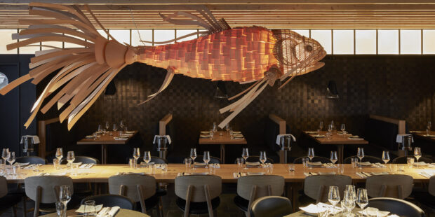 A restaurant interior with unique wooden fish sculpture and neatly set tables