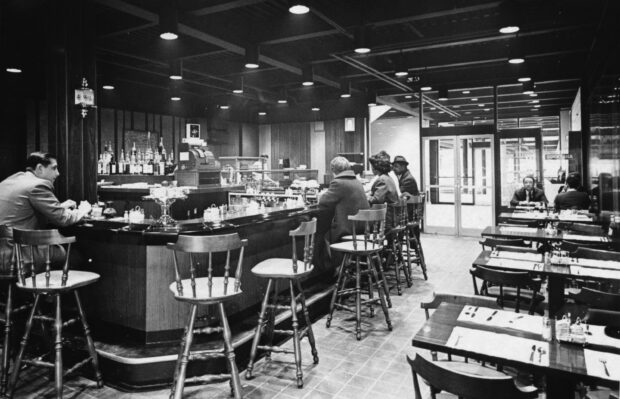 Vintage restaurant interior showing customers seated at the bar and dining tables