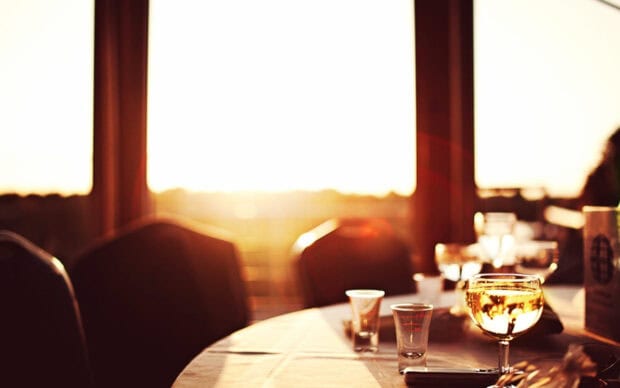 A glass of wine on a table set in a restaurant during sunset light