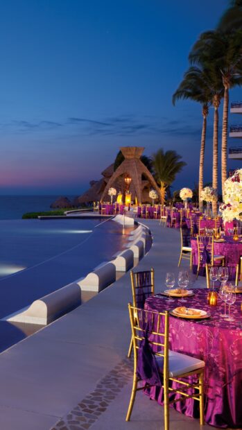 Outdoor restaurant setting with elegant dining tables near the ocean at sunset