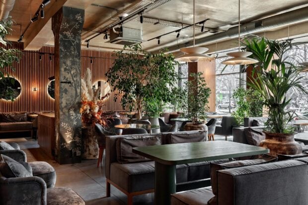Modern restaurant interior with plants and cozy seating arrangement in a trendy space