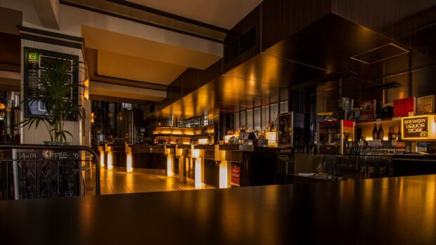 Modern restaurant interior with warm lighting and bar area reflecting on surfaces
