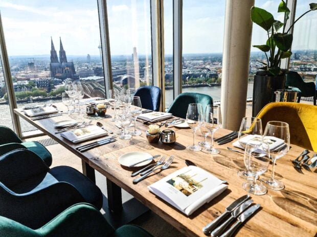 A restaurant table setup with glassware and cutlery overlooking a cityscape through large windows