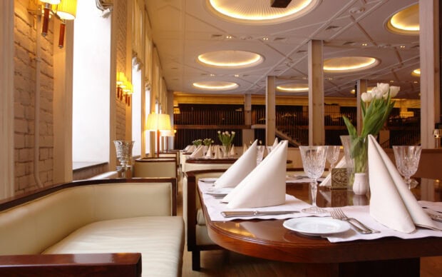 Elegant restaurant interior with a cozy seating area and neatly arranged table settings including napkins and glassware