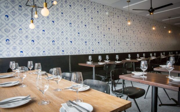 Elegant restaurant interior with neatly arranged tables and creative wall d&eacute;cor featuring portraits