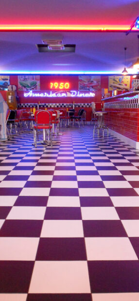 Retro American diner interior with checkered floor and neon signs in vibrant colors