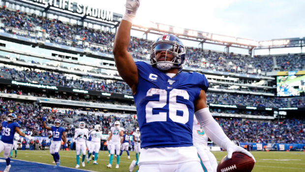 Saquon Barkley celebrates a touchdown wearing a blue football uniform on the field at the stadium