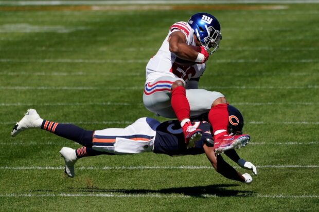 Saquon Barkley running with the ball while a defender tackles him during a football game