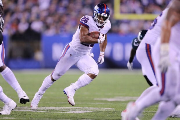 Saquon Barkley running with the football during a game in white uniform