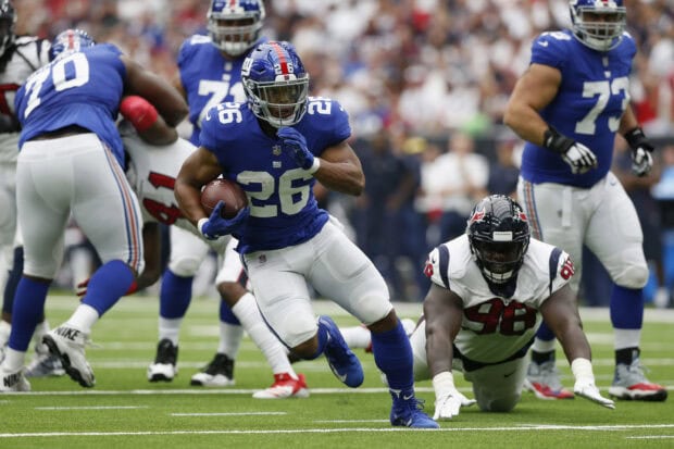 Saquon Barkley running with the football during an NFL game in blue uniform