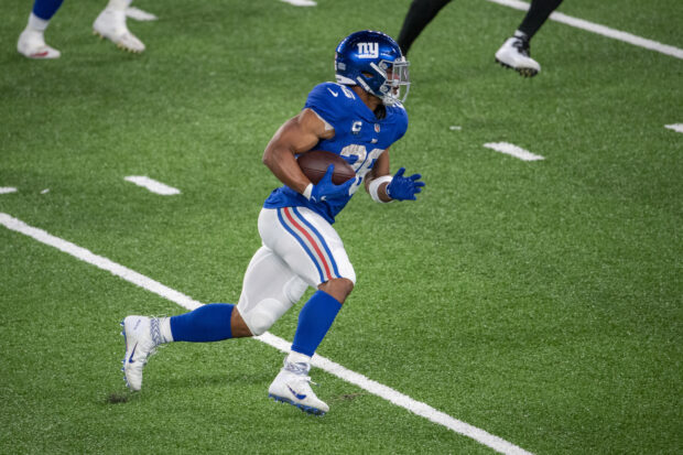 Saquon Barkley running with the football on the field during a game