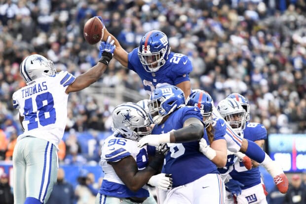 Saquon Barkley leaping to catch a football during a game with intense Dallas Cowboys defense