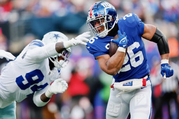 Saquon Barkley carrying the football while evading a defender during an NFL game