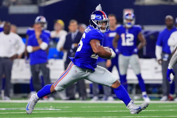 Saquon Barkley running on the football field during a game with the New York Giants jersey