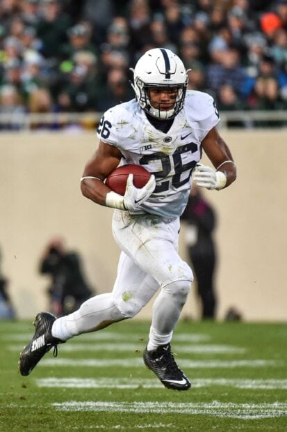 Saquon Barkley running with football during a game in football uniform