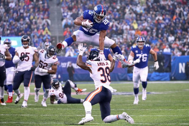 Saquon Barkley leaps over a defender during an intense football game action