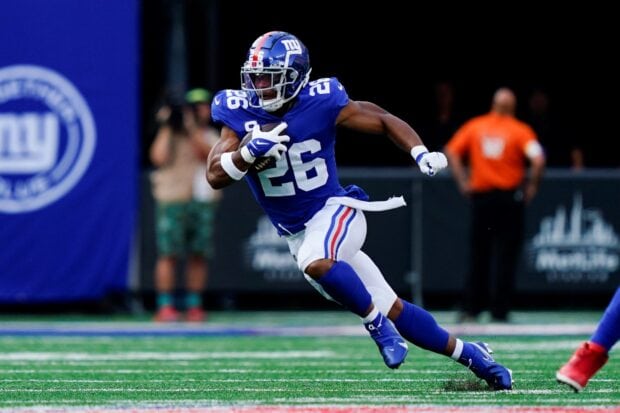 Saquon Barkley running with the football during a game in the blue Giants uniform