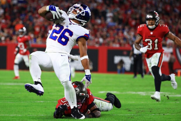 Saquon Barkley carrying the football while evading a tackle in an intense NFL game