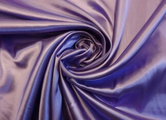 Close up of satin fabric texture with smooth folds and purple color silk feeling