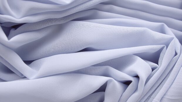 Close up of satin texture with soft folds and smooth surface in light lavender color