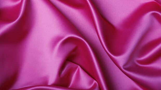 Smooth satin fabric in bright pink with elegant folds and texture