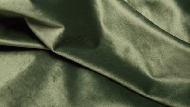 Smooth satin fabric in dark green with natural folds and texture