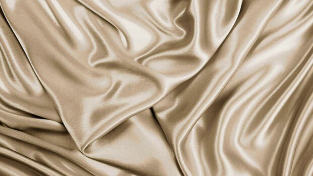 Smooth satin fabric texture in beige color with elegant folds and light reflections