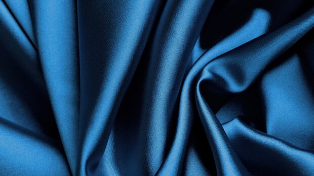 Close up of blue satin fabric with smooth texture and elegant folds