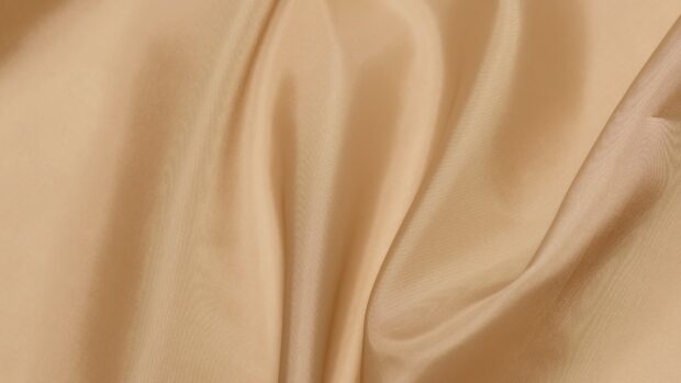 Smooth satin fabric with soft beige satin texture and elegant folds
