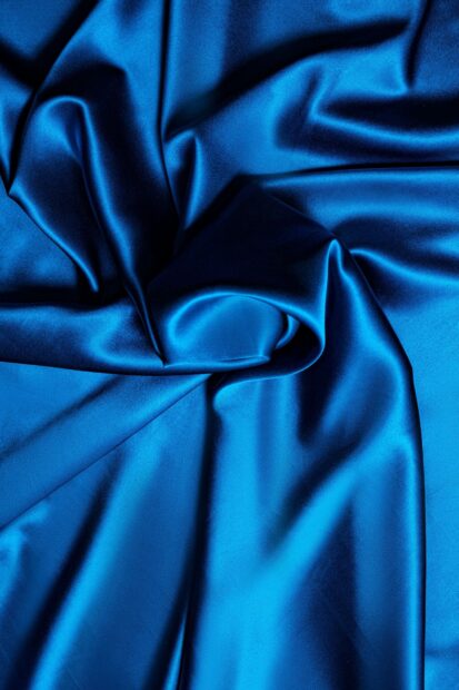 Smooth blue satin fabric folds creating elegant texture and satin effect