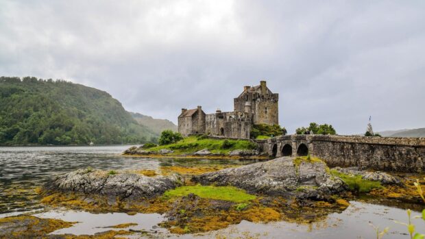 Historic Scotland castle on a rocky island surrounded by water and green hills