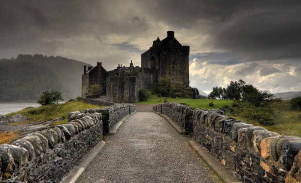 Historic stone castle in Scotland surrounded by lush greenery and a stone pathway