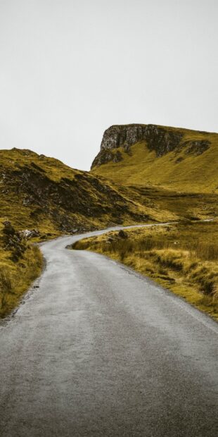 A winding road through the rugged hills of Scotland landscape