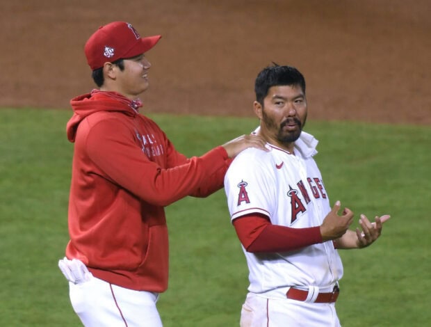 Shohei Ohtani interacting with a teammate on the baseball field during a game