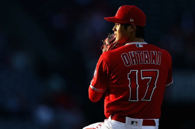 Shohei Ohtani baseball player preparing to pitch on the field wearing a red jersey with number 17