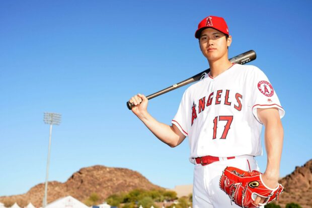Shohei Ohtani holding a baseball bat and glove in Los Angeles Angels uniform