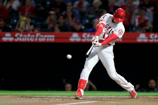 Shohei Ohtani swinging a baseball bat during a game wearing his Angels uniform
