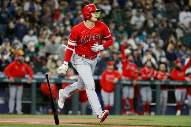 Shohei Ohtani swinging at the baseball during a game in a red angels uniform