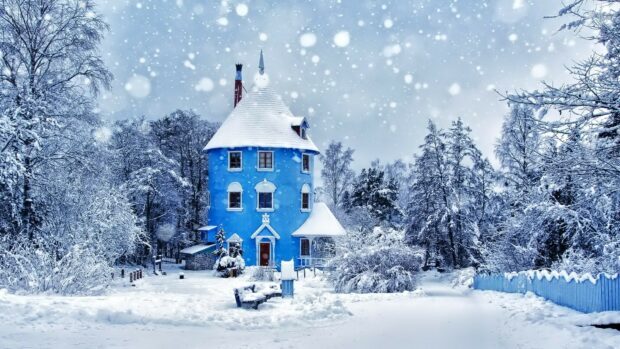A snowy winter landscape with a blue house surrounded by snow covered trees and snowfall