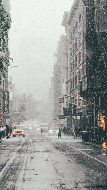 Snowfall covering city streets with people and cars in a winter scene