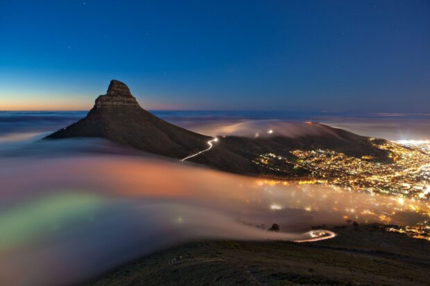 Night view of South Africa mountain with glowing city lights and flowing mist