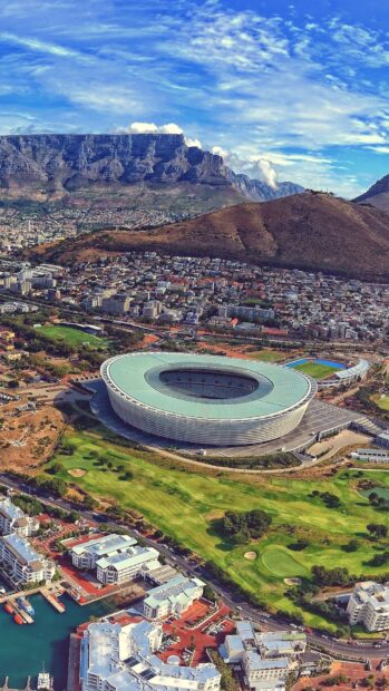 Aerial view of South Africa stadium surrounded by city and mountains under blue sky