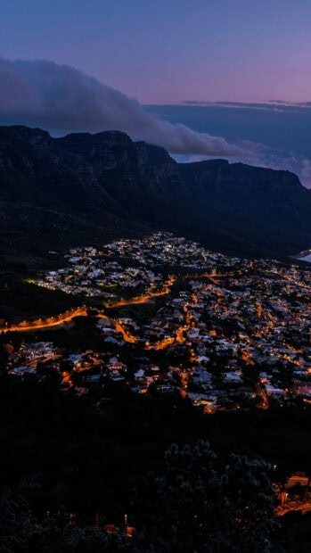 Night view of South Africa city lights below the mountain ridge