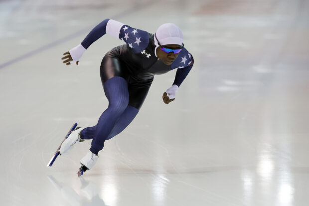 A speed skating athlete wearing a stars patterned suit in a competitive race on ice