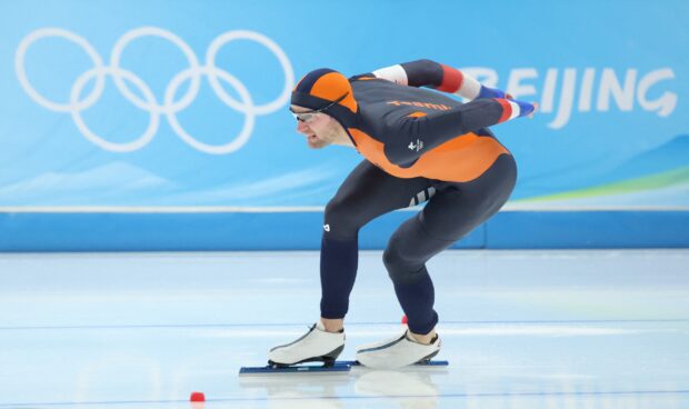 Male athlete in speed skating suit competing on ice during speed skating event