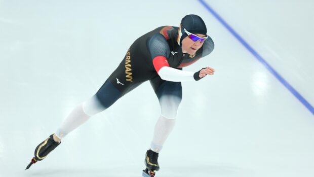 A speed skater from Germany competing on the ice in a racing suit