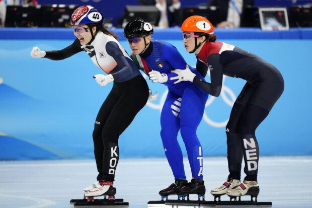 Three female speed skating athletes competing closely during a race on ice rink