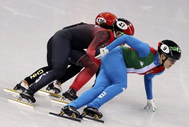 Two speed skating athletes compete closely on the ice during a race