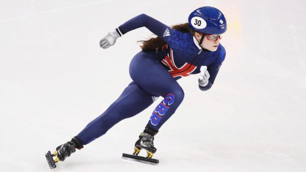 A female speed skater in blue GBR suit racing on ice during a competition