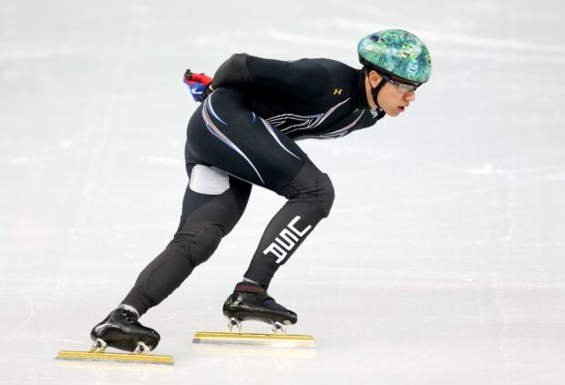 Male speed skater wearing protective gear and helmet during competition